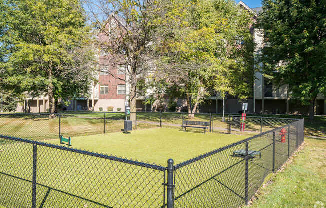 a fenced in area with a tennis court and a bench