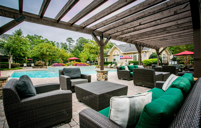 a covered patio with wicker furniture and a swimming pool