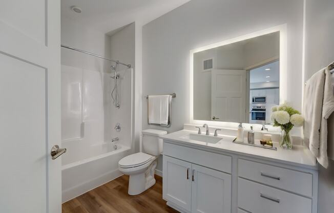 a white bathroom with a large mirror and a white toilet and sink