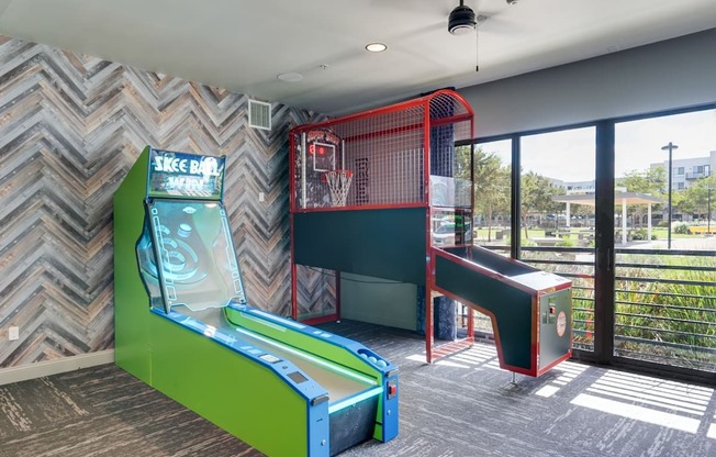 A room with a green and red arcade game and a basketball hoop.