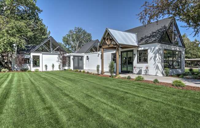 A white house with a black roof and a green lawn in front.