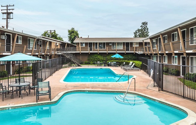 A swimming pool surrounded by a black fence and chairs.