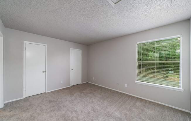 an empty bedroom with a large window and carpeted flooring  at Shadow Ridge, Arlington, Texas