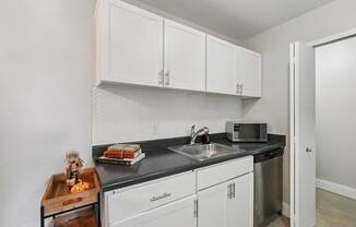 A kitchen with white cabinets and a black countertop.
