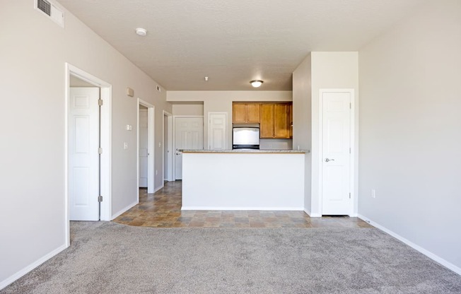 A spacious living room with a kitchen area in the background.