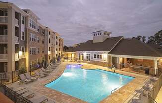 A swimming pool surrounded by lounge chairs and apartment buildings.