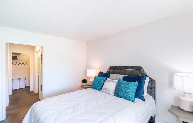 A bedroom with a white bed and blue pillows.