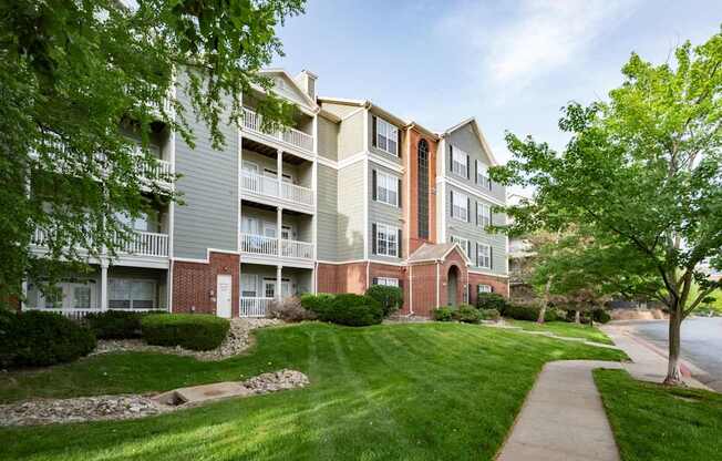 A large apartment complex with a well-maintained lawn and trees.