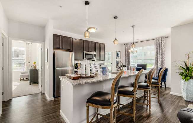 A kitchen with a white island and black chairs.