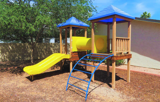 a playground with a yellow slide and a blue monkey bars