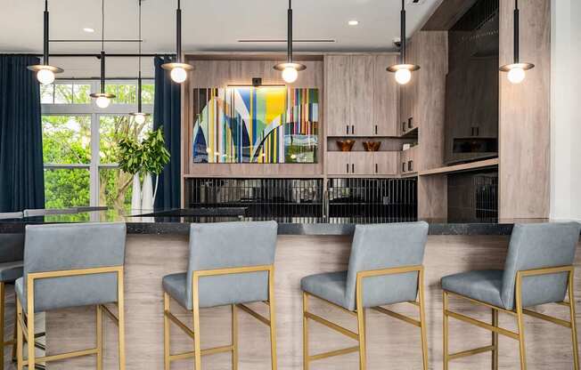 A modern bar area with grey chairs and a wooden counter.