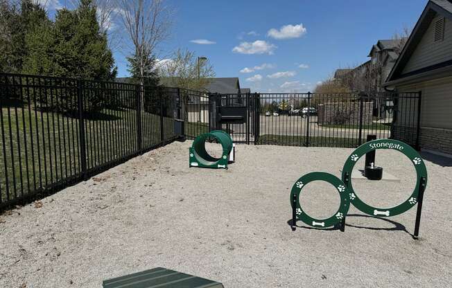 A playground with a green slide and a black fence.