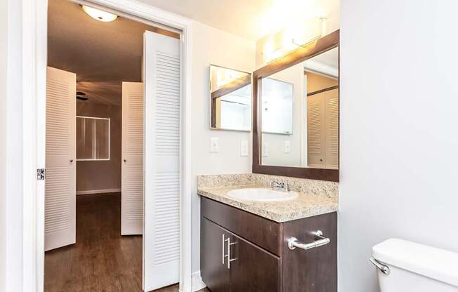 A bathroom with a sink, mirror, and toilet.