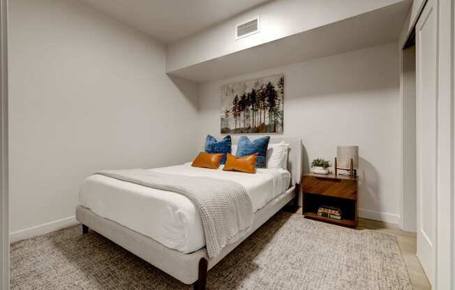 bedroom with white walls and a white bed with orange and blue pillows