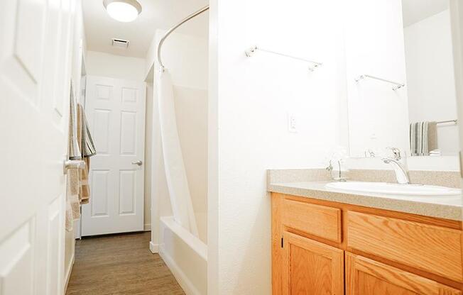 A bathroom with a wooden vanity and a white sink.