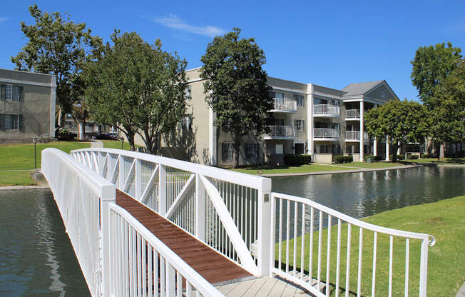 A white railing over a body of water with buildings in the background.
