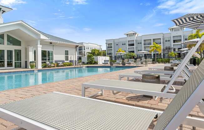 a swimming pool with lounge chairs and buildings in the background