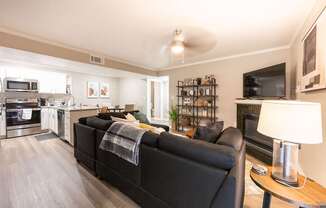 A black couch with a blanket on it sits in a living room.
