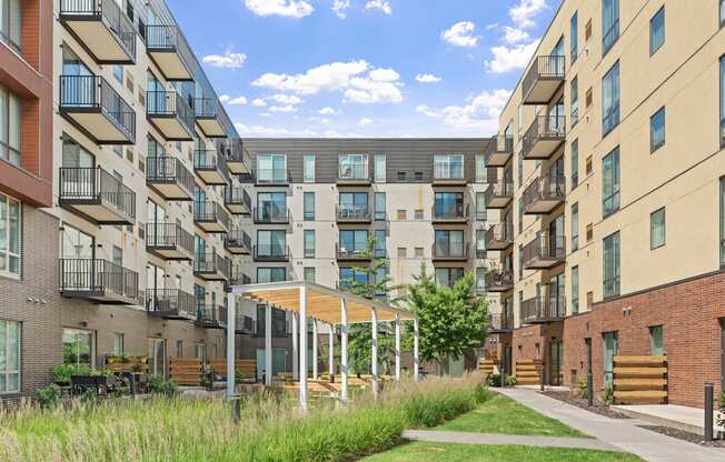 A row of apartment buildings with balconies and a grassy area in front.