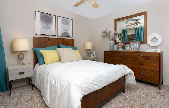 A bedroom with a bed, dresser, and two lamps.