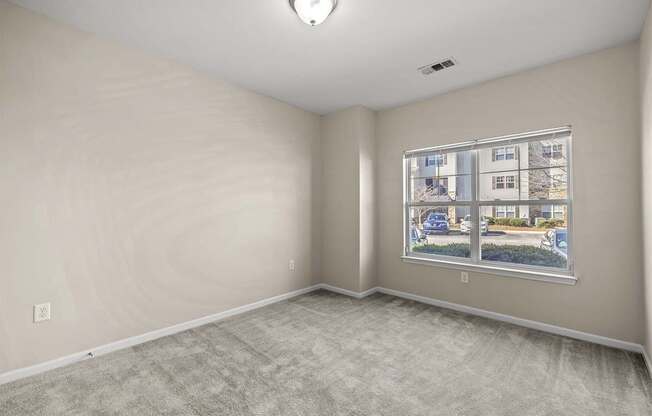 A room with a window showing a view of a street with cars and houses.