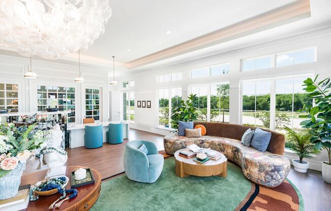 Sunlit leasing office with expansive windows, curved seating, and layered textures that frame green views and invite you home.
