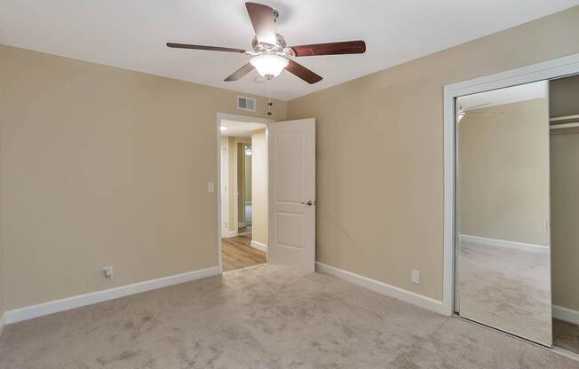 A room with a ceiling fan and a mirror on the wall.