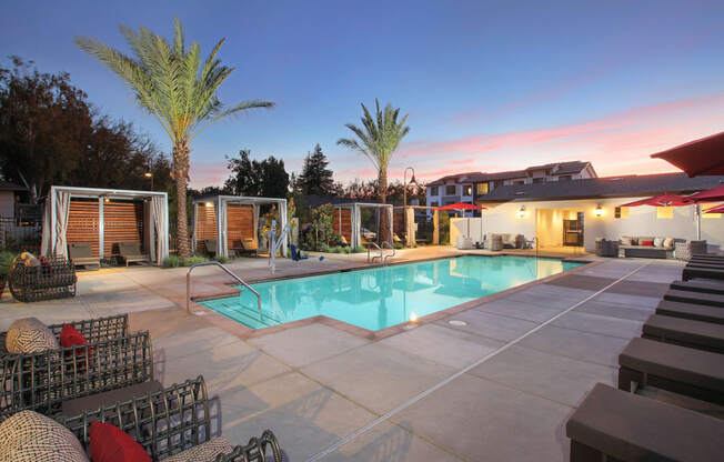 A poolside area with lounge chairs and palm trees.