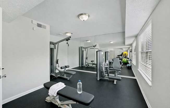 A gym with a variety of equipment including a bench, weights, and a mirror.