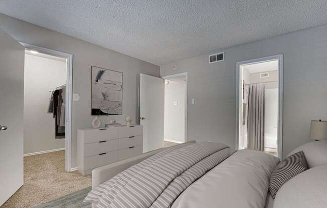 A bedroom with a large bed and a dresser with a mirror.