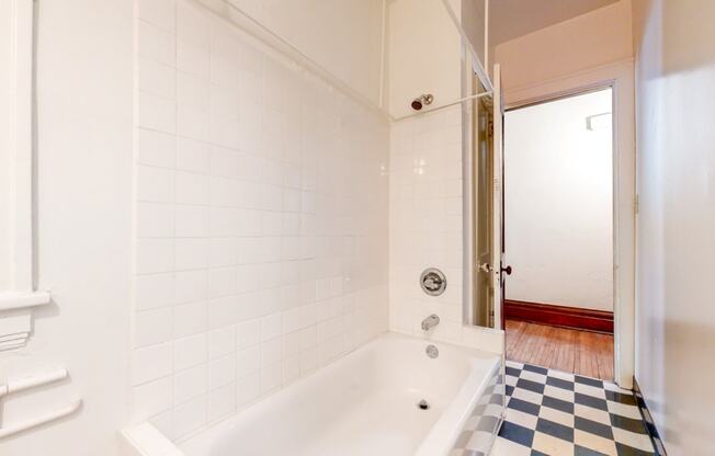 Bathroom with White Tiles and a Black and White Checkered Flooring at The Park Apartments in Minneapolis, MN