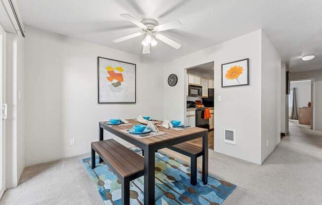 A dining room with a table and chairs and a ceiling fan.