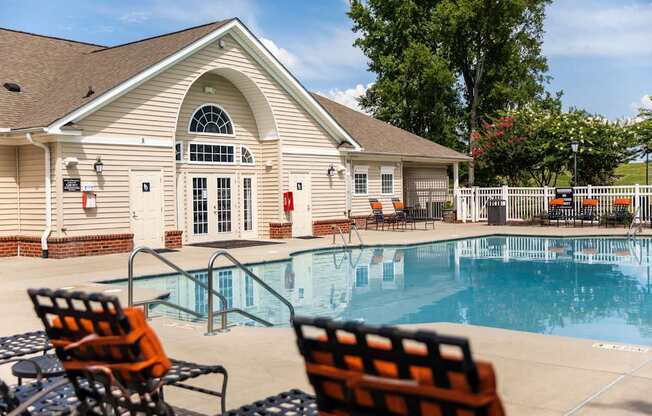 A poolside scene with a building and chairs.
