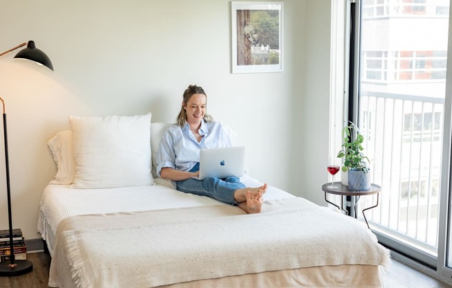 a woman sitting on her bed with a laptop