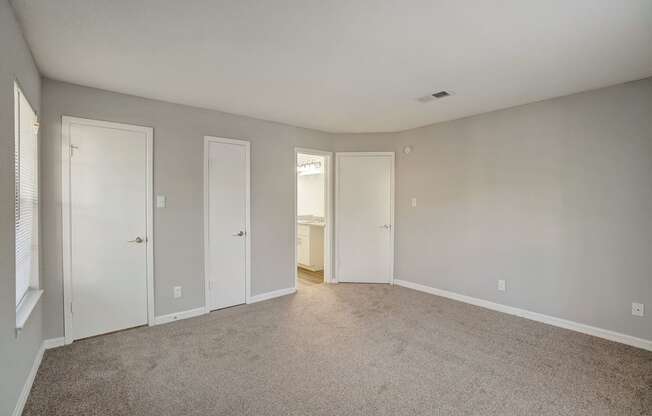 an empty living room with white doors and carpet