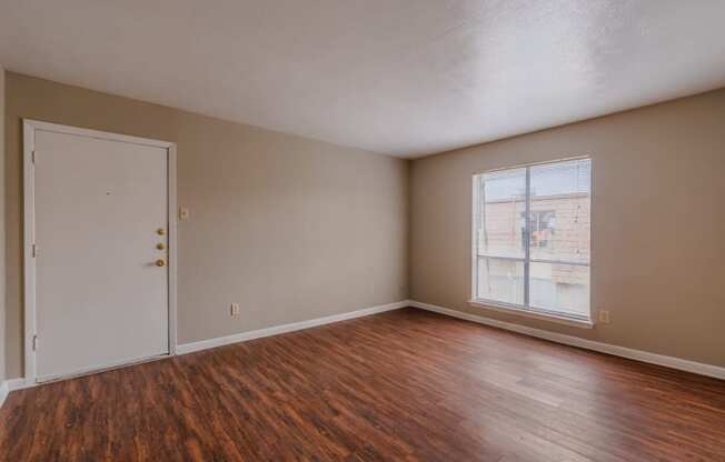 an empty living room with wood flooring and a door
