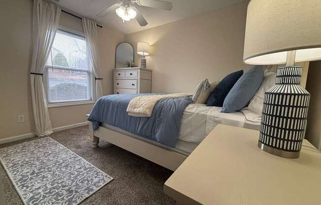 A bedroom with a bed, dresser, and window.