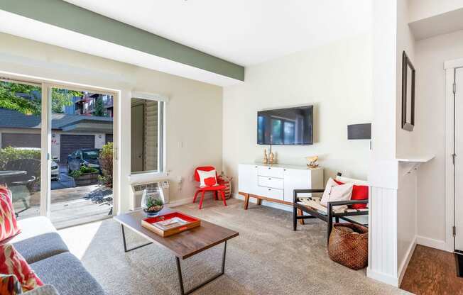 a living room with white walls and a sliding glass door that leads to a patio at Mullan Reserve Apartments, Montana, 59808