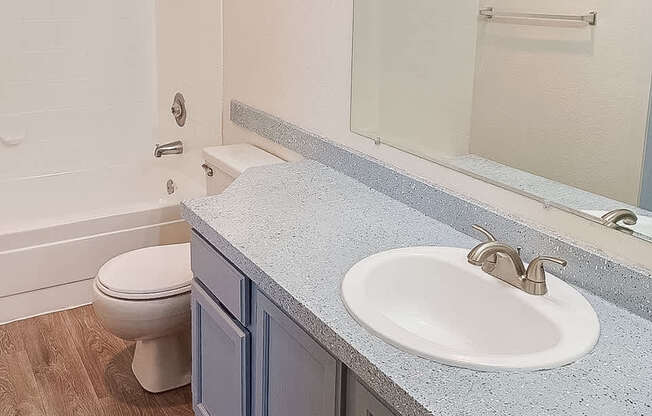 A bathroom with a toilet, sink, and mirror.