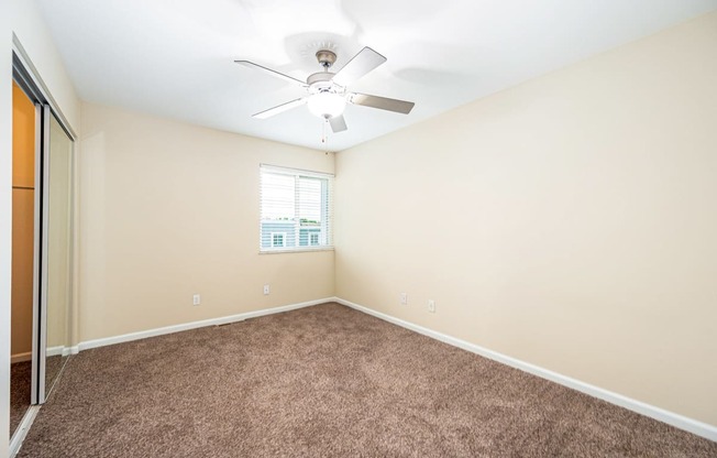 an empty room with carpet and a ceiling fan