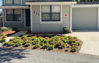 A grey house with a red and white sign on the garage door.