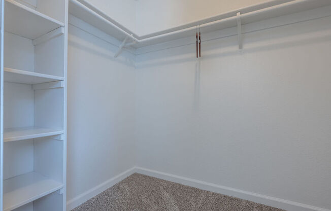 a walk in closet with white walls and shelves