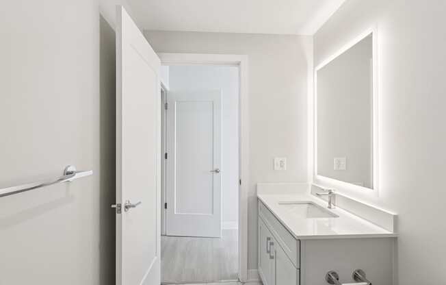 A white bathroom with a sink, mirror, and towel rack.