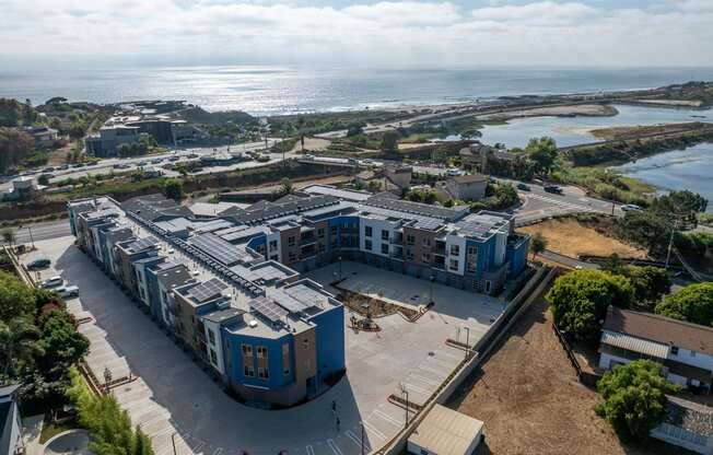 an aerial view of an apartment complex with the ocean in the background