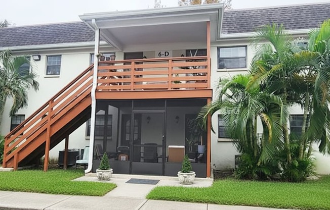 A white house with a wooden staircase leading to the second floor.