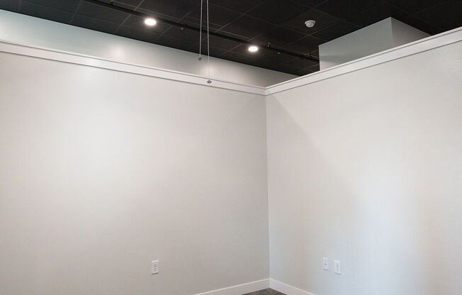 an empty room with a ceiling fan and white walls