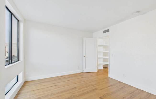 A white room with a wooden floor and a door on the right.