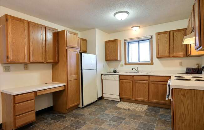 Kitchen with wooden cabinets and a white refrigerator at Parkwest Gardens West Fargo, ND 58078 