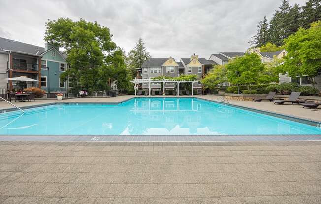 A swimming pool surrounded by trees and houses.