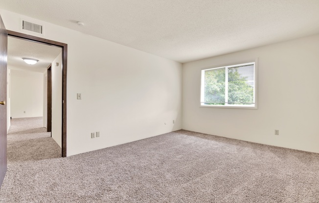 A room with a carpeted floor and a window.